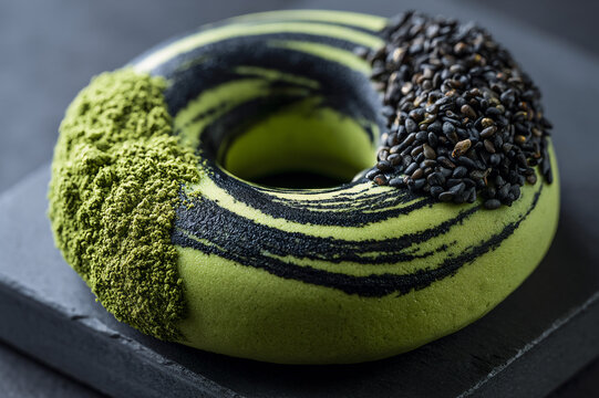 Close up of a gourmet matcha green tea donut with black sesame seed swirl