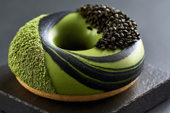 Close up of a gourmet matcha green tea donut with black sesame seed swirl