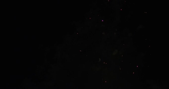 Many fireworks launching into night sky with smoke trails and exploding into beautiful colors