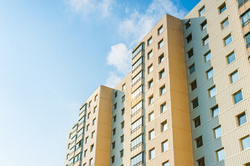 Fototapeta premium Modern beige residential apartment building under bright blue sky.