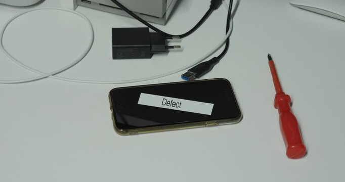 Technician sticking a defect label on a broken smartphone after inspection, marking the device as not working.
