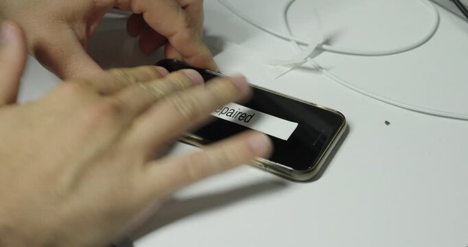 Technician replacing a defect label with a repaired label after successfully fixing a smartphone.