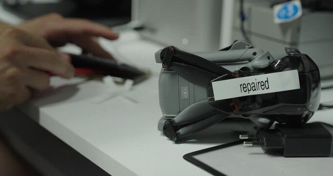 Smartphone marked as repaired while another phone is being fixed in the background at an electronics workstation.