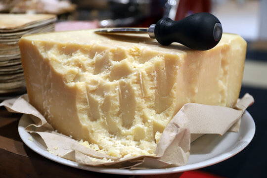 cu&ntilde;a de queso parmesano en un plato con cuchillo de queso parmesano