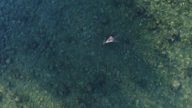 Drone view of a school boy swimming in the sea. High quality 4k footage