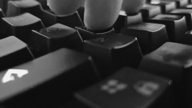 A close-up, monochrome macro shot of a finger typing on a mechanical keyboard. Black and white