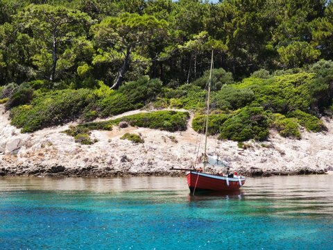 Red boat anchored in turquoise waters of Bademli Bay, Dikili, Izmir, Turkey