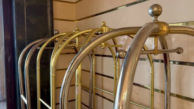 A hotel luggage cart with a gold frame and red fabric. It is positioned on a patterned floor, ready for transporting guest belongings