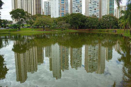 Paisagem do Parque Flamboyant em Goiania, mostrando o lago com bosque e pr&eacute;dios com reflexos na &aacute;gua do lago.