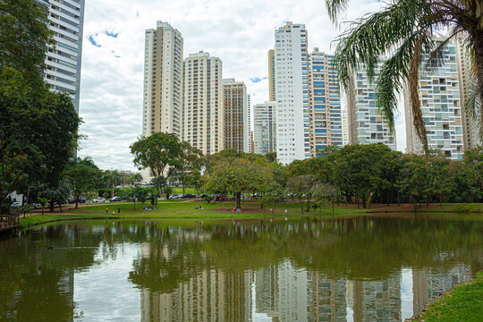 Paisagem do Parque Flamboyant em Goiania, mostrando o lago com bosque, pr&eacute;dios e ceu nublado ao fundo.