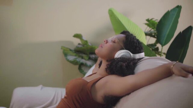 Young latina woman meditating on couch with headphones
