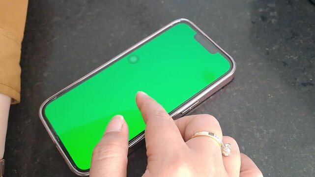 Asian woman hand with ring and bracelet using green screen phone. Scrolling, tapping, social media, unlock. 4K video for iphone, green screen, tech background, technology background, app, mockup.