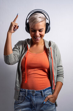 Cool young urban girl with short gray enjoying while listening to music on studio headphones 