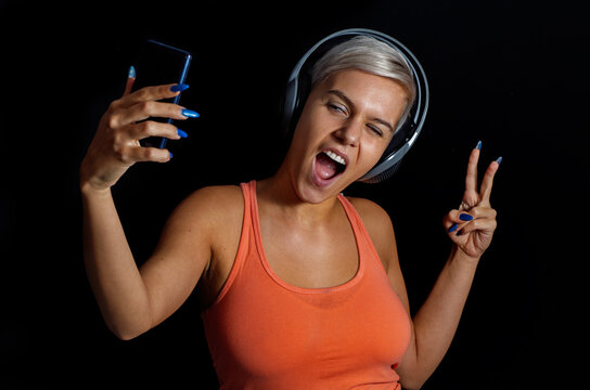 Cool girl young girl with headphones taking selfie with her phone , on dark background 