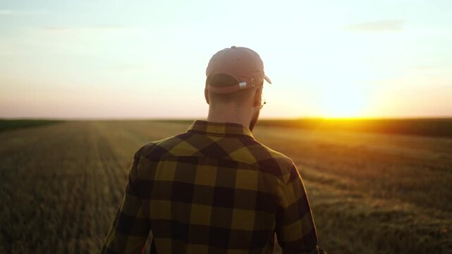 Silhouette of a farmer walking across an open field during golden hour, representing farming lifestyle, rural work and agriculture.