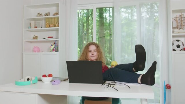 Student studying with laptop computer. Online learning during school lesson. Healthy snack and apple nearby. Homework at home desk. Kid learning in home school. Child studying in online class.