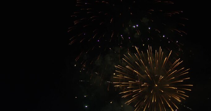 Massive Bursts Of Light From Majestic Aerial Fireworks Exploding Into Smokey Night Sky
