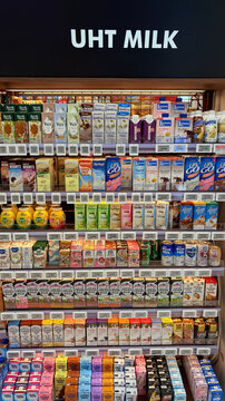 A shelf filled with various brands of UHT milk and plant-based milk alternatives. The products are arranged neatly in colorful packaging, showcasing diversity in options.