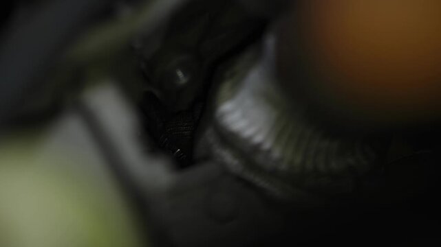 Metal socket wrench tool laying inside a dark car engine compartment