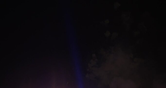 Blue Spotlights Cutting Through Smokey Night Sky After Firework Show