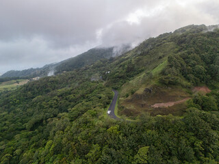 Naklejka premium Scenic view of a winding road through green hills and clouds