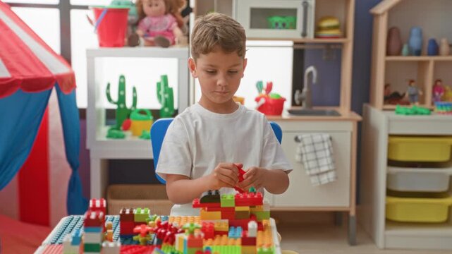 Boy placing plastic block with hands while stacking colorful bricks at a play table inside a building playroom; concentration creativity.