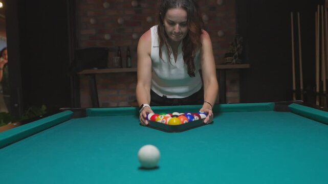 Woman racking pool balls and breaking with cue ball