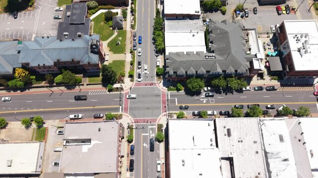 Aerial perspective of a bustling intersection in Brevard, North Carolina, featuring vehicles, buildings, and lush greenery in the urban landscape