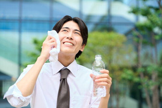 暑い屋外で汗を拭くビジネスマン