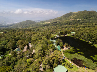 Naklejka premium Cloudy sky above forest and pond in mountain area during daytime
