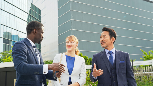 街で外国人ビジネスパーソンを案内する日本人ビジネスマン