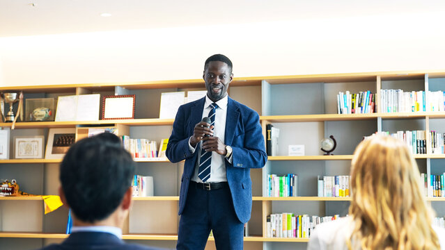 A black businessman giving a speech in front of an audience.