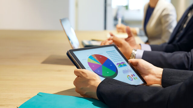 Business professionals holding a meeting while looking at a tablet screen.