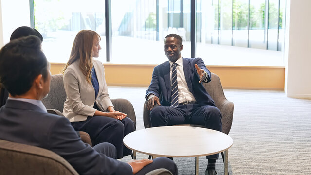 A group of multinational businesspeople conversing in the lobby.