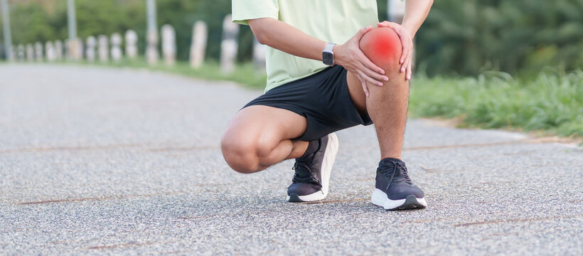 Young adult male runner with knee pain from ACL injury or patellofemoral syndrome. Man having joint ache, ligament tear or patellar tendinitis during running. Sports medical and healthcare concept