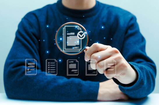 Professional business person using a magnifying glass to inspect digital documents and online contracts, representing audit, data verification, compliance, quality control, and information review.
