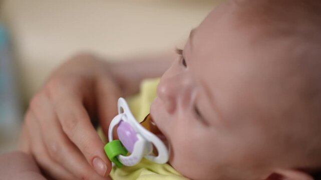 Mother comforting her newborn baby sleeping with a pacifier