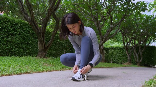 Asian sport woman tying sneaker lance in park
