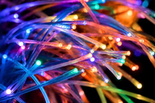 Chaotic tangle of illuminated fiber optic cables glowing brightly at their cleanly cut terminal ends