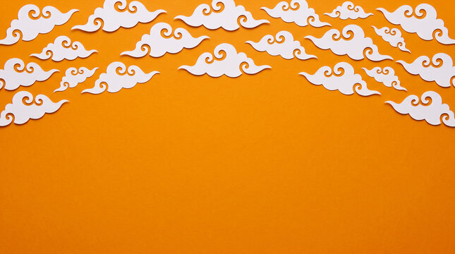 Halloween orange background featuring spooky cloud paper cut out top border, copy space for Halloween party invitation, greeting card, banner, poster, flyer and seasonal design