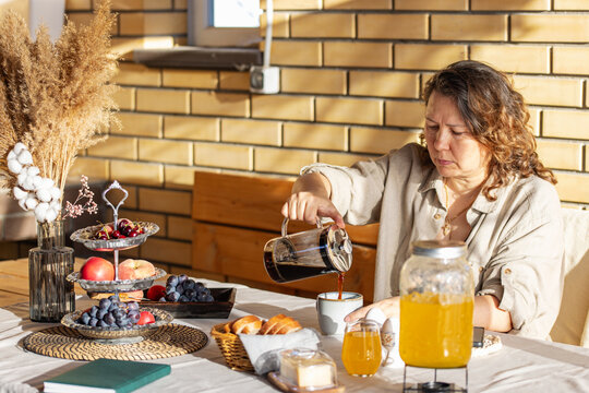 Woman in outdoors gazebo slowly eats breakfast alone