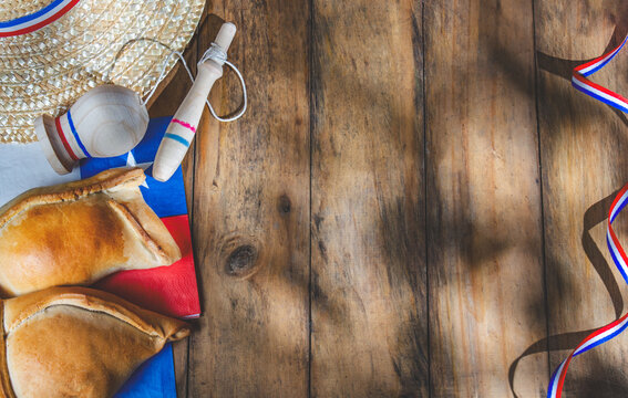 Chilean independence day concept. fiestas patrias. Tipical baked empanadas, fat and play emboque. Decoration for 18 september party day, wooden background