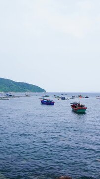 In Dak Lak, Vietnam, many fishing boats are in the water. People are setting up their equipment and getting ready for a fishing trip. It is a busy morning on the water.