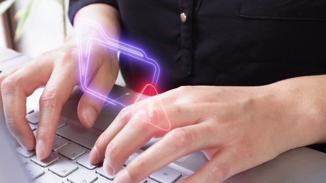 Hands typing on a laptop keyboard. Fingers press the keys with a focused rhythm. Folder icons with a warning sign.