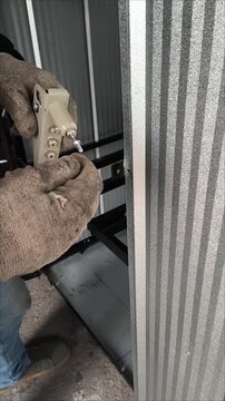 Construction worker fixing a metal sheet structure with a manual riveting tool