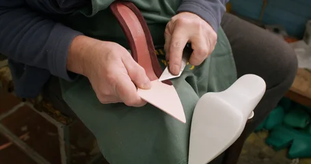 Footwear manufacturing. Shoes factory. Master hands using metal stationery knife working with sole in professional workshop. © golubovy