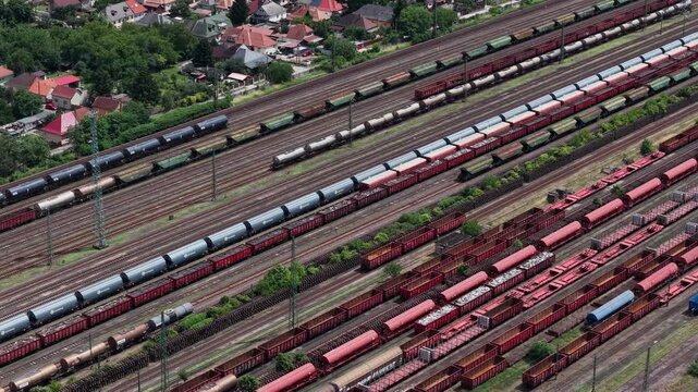Multiple freight trains and cargo wagons are stationed at a busy industrial marshalling yard in suburban Hungary.