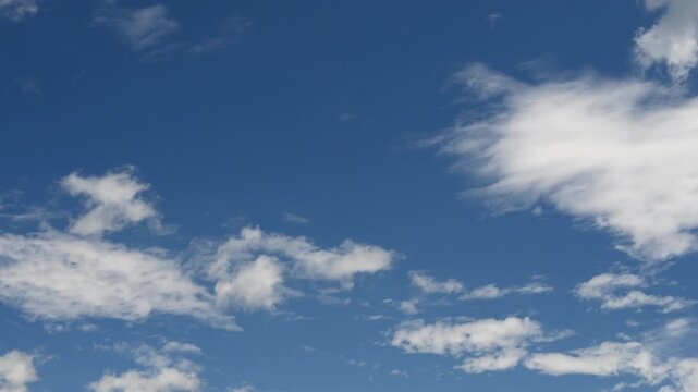 White clouds drift across a clear blue sky, creating a serene and expansive natural background.