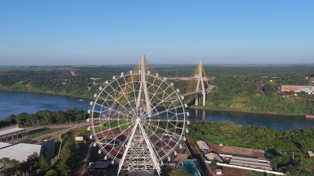 Yup Star Ferris wheel overlooking the Paran&aacute; River and Integration Bridge, Foz do Igua&ccedil;u, Paran&aacute;, Brazil, at the Triple Frontier bordering Paraguay and Argentina, drone forward flyover