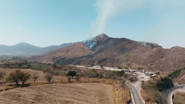 Distant drone perspective of a destructive wildfire creating a large smoke plume in Comala, Colima